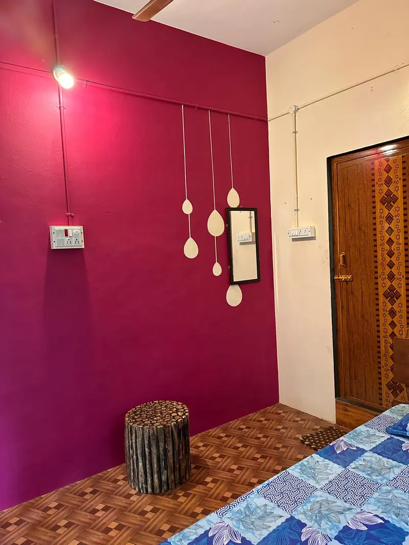 Lavender room — bright non-AC bedroom with hanging decor and wooden stool