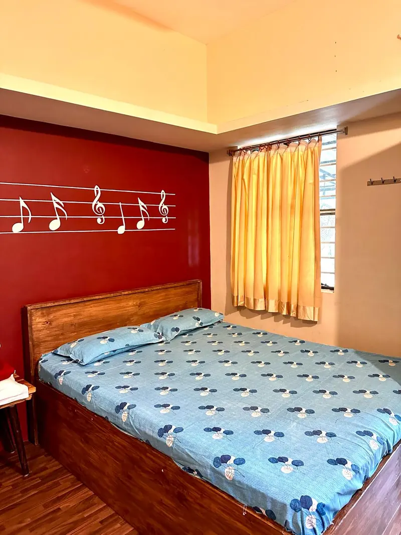 Non-AC bedroom with patterned bedding and wooden bed frame
