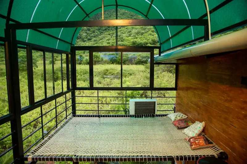 Covered sit-out with a hanging cot under the green roof