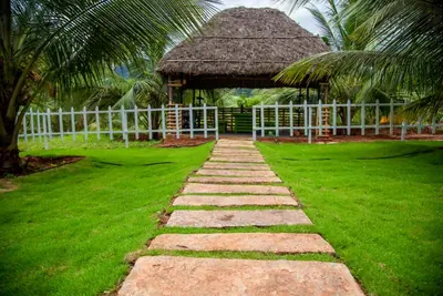 Thatched gazebo at the end of a stone path across the farm lawn