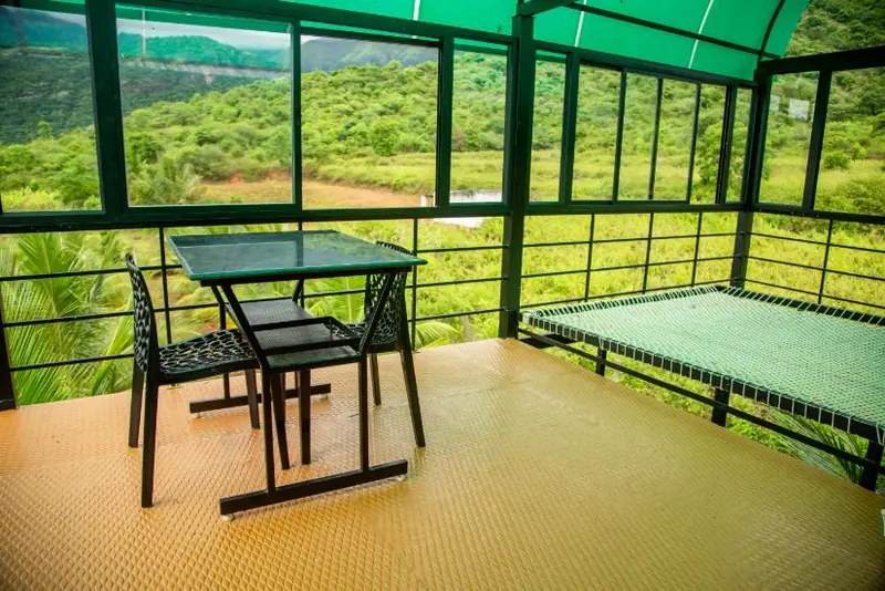 Terrace sit-out with hanging cot and table looking over the valley