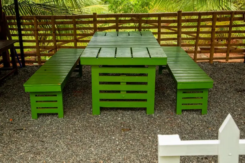 Green picnic table and benches on the gravel courtyard
