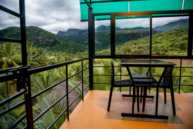 Terrace dining set under a green canopy with the Western Ghats beyond
